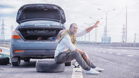 man stuck on the road calling for help because of flat tire