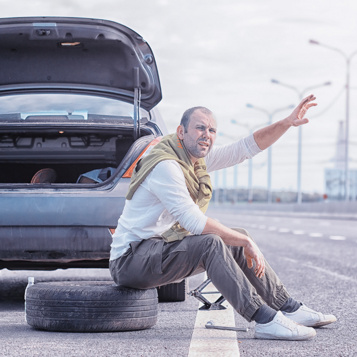 man stuck on the road calling for help because of flat tire