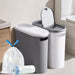 Two trash bins with a bag and roll of liner in a bathroom setting