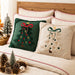 Green and beige Christmas tree cushions on a bed