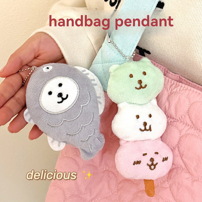 Fish cake and dango plush charms hanging on a pink handbag