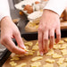 Hands placing cut-out cookies on a baking tray