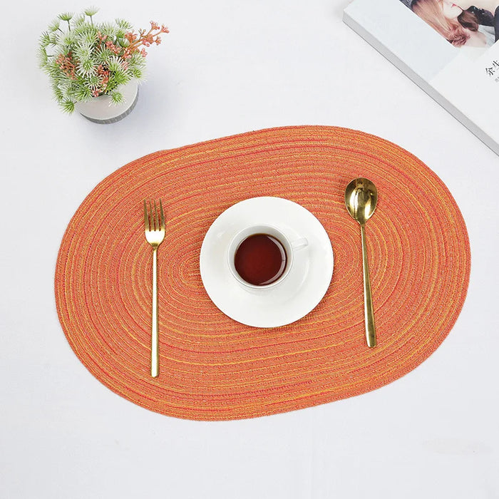 Orange oval braided placemat with a cup and cutlery