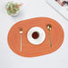 Orange oval braided placemat with a cup and cutlery