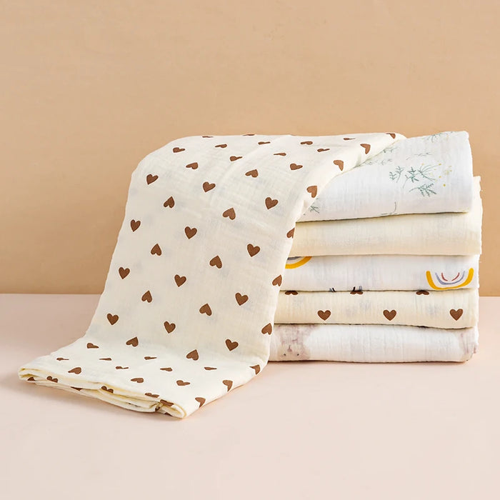 Stack of folded muslin baby blankets, heart print on top