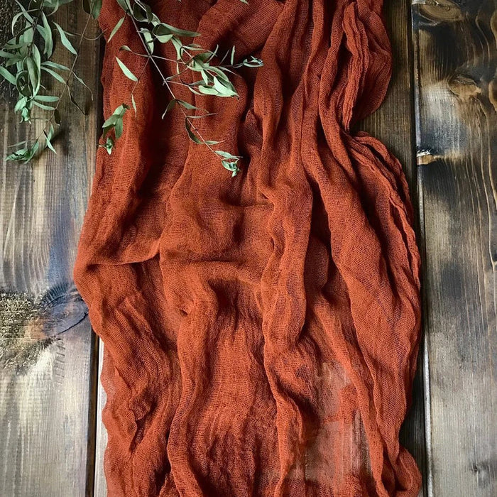 Rust gauze table runner on a dark wooden table