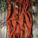 Rust gauze table runner on a dark wooden table