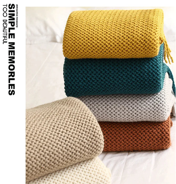 Stack of knitted throws in yellow, teal, grey and rust