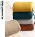 Stack of knitted throws in yellow, teal, grey and rust