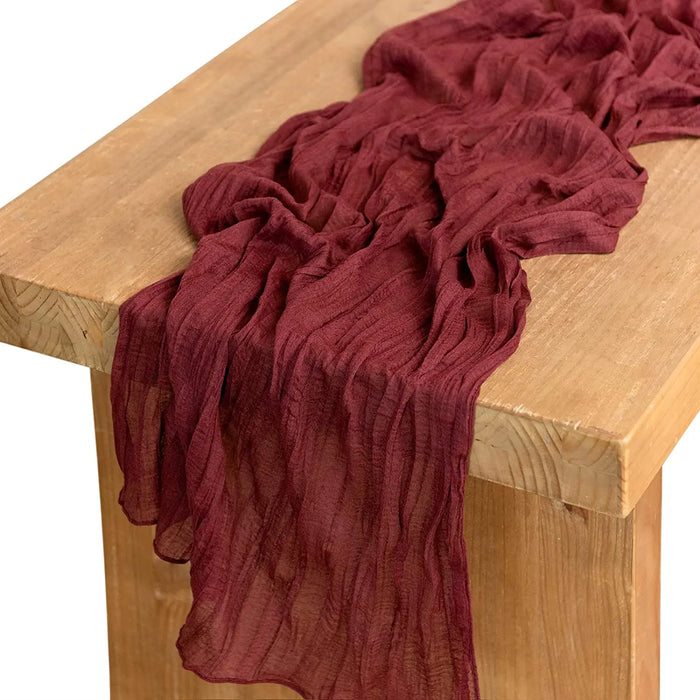 Burgundy gauze table runner on a wooden table