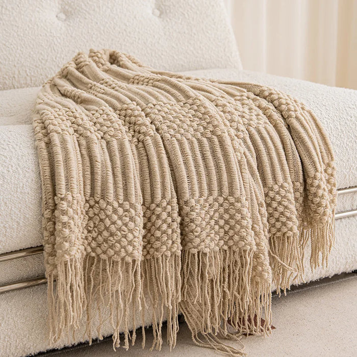 Khaki knitted throw blanket with tassels on a sofa