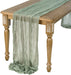 Sage gauze table runner draped over a wooden table