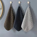 Brown, navy and grey hand towels hanging from hooks