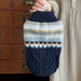 Navy cable-knit dog sweater held up by the collar