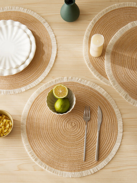 Natural round placemats with fringe on a dining table