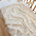 Pink forest print muslin blanket in a crib