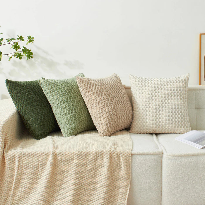 Textured knit cushions in green, beige and cream on a daybed