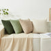 Textured knit cushions in green, beige and cream on a daybed