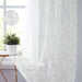 White lace curtain beside a plant on a windowsill