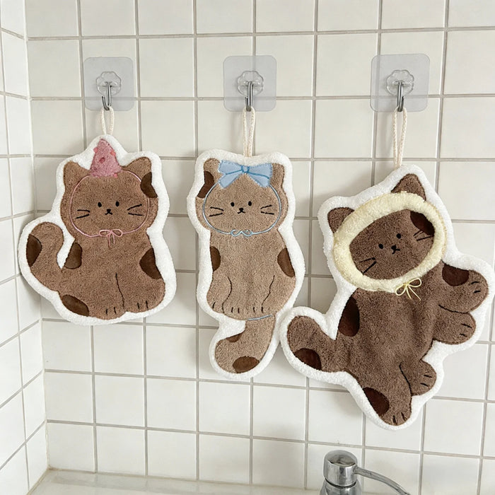 Three cat hand towels on wall hooks above a sink