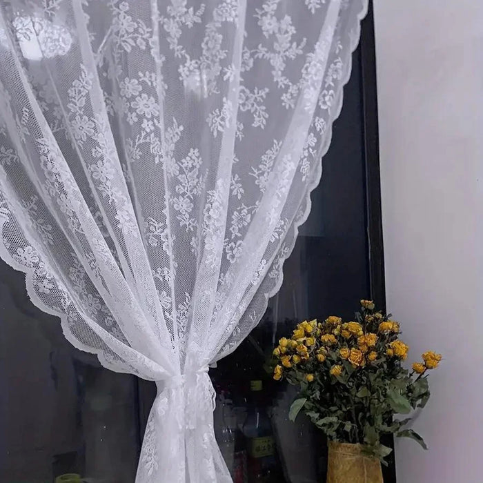 White lace curtain tied back against a dark window