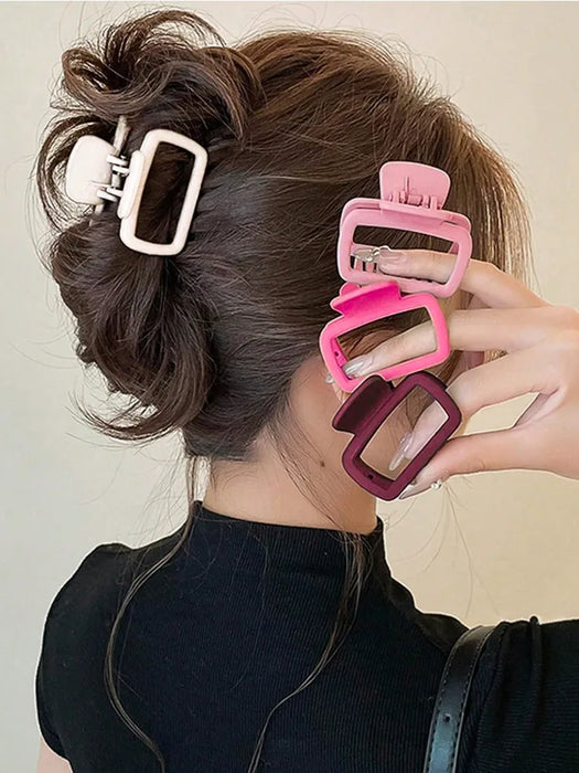 Square claw clips in white, pink, magenta and wine red beside a twisted updo