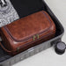 Brown toiletry bag packed in a suitcase