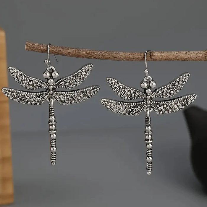 Pair of carved silver dragonfly earrings on a twig