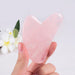 Hand holding a pink heart-shaped gua sha tool