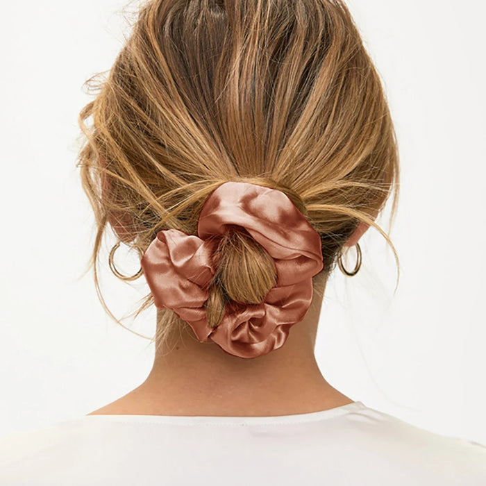 Woman wearing a pink silk scrunchie in a low bun