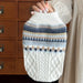 Beige cable-knit dog sweater held up by the collar