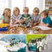 Children building solar robots at a table, with boat and car models