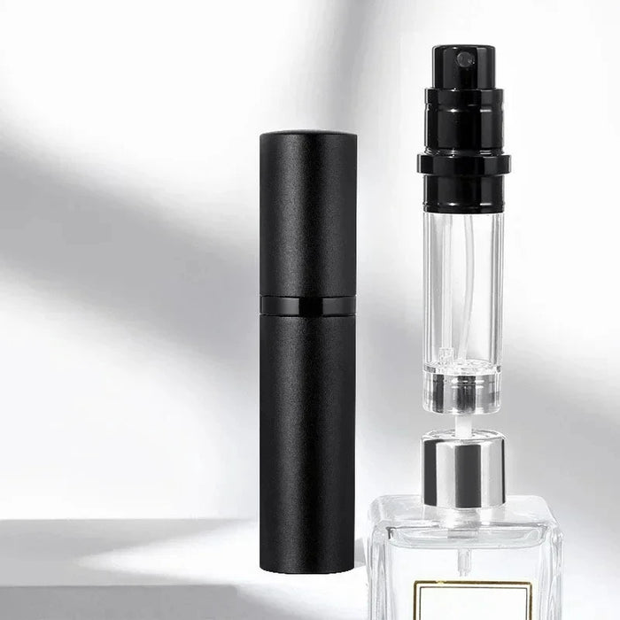 Black atomizer and its clear inner bottle beside a perfume bottle