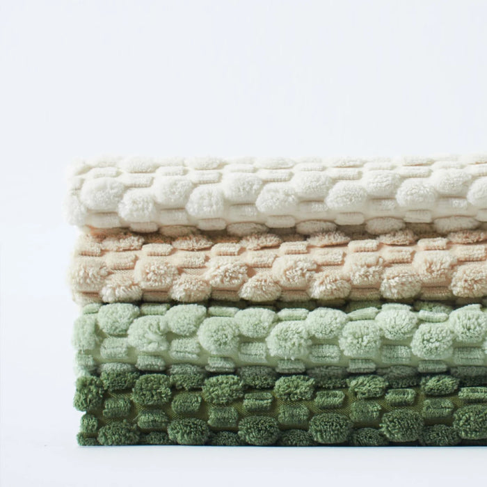 Stack of folded knit fabric in cream, beige and green