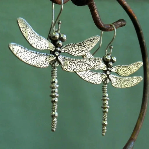Silver dragonfly drop earrings hanging on a branch