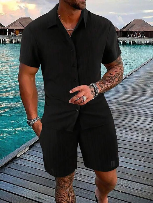 Man in a black short sleeve shirt and shorts set by the sea