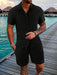 Man in a black short sleeve shirt and shorts set by the sea
