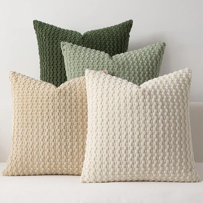 Green, sage, beige and cream textured knit cushions on a sofa