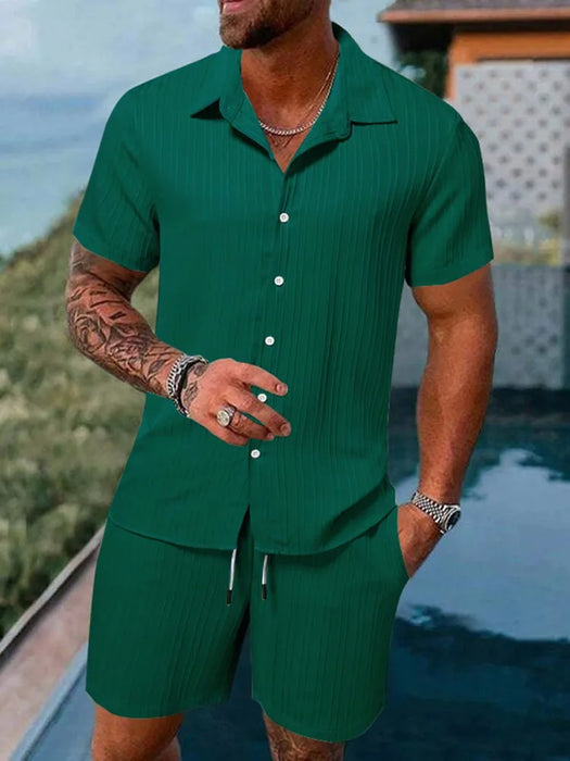 Man in a green short sleeve shirt and shorts set by the water