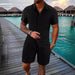 Man in a black short sleeve shirt and shorts set on a boardwalk