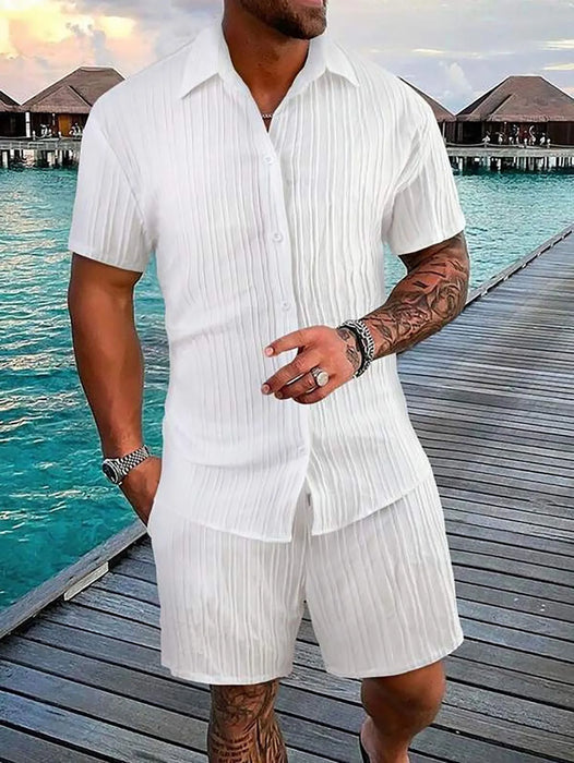 Man in a white short sleeve shirt and shorts set on a boardwalk