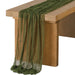 Olive gauze table runner over a wooden table