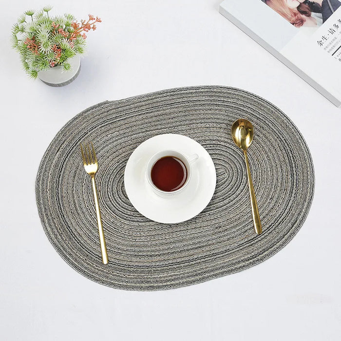 Grey oval braided placemat with a cup and cutlery