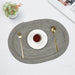 Grey oval braided placemat with a cup and cutlery