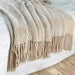 Khaki knitted throw with tassels on a white rug