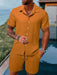 Man in an orange short sleeve shirt and shorts set