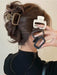Four square matte claw clips in brown, white and black held beside a twisted updo