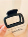 Black square claw clip in hand, about 5 cm wide
