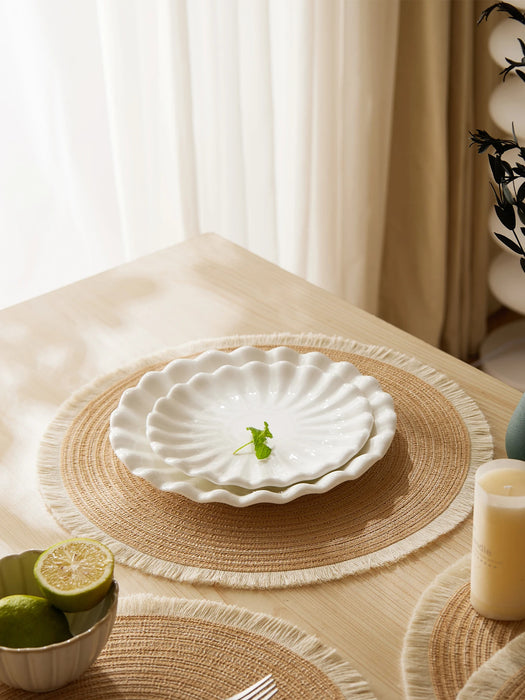 White plate on a round woven placemat by a window