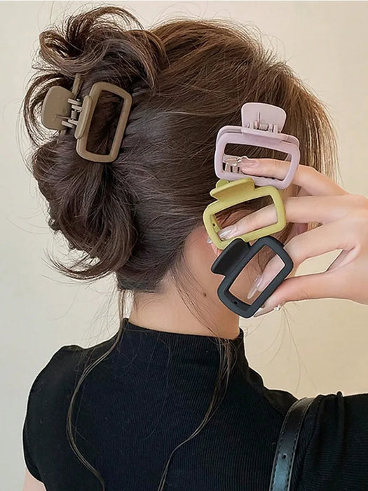 Square claw clips in brown, pink, olive and black beside a twisted updo